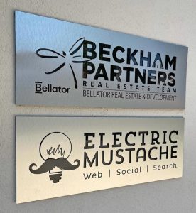 silver building sign with electric mustache design logo cutout in black